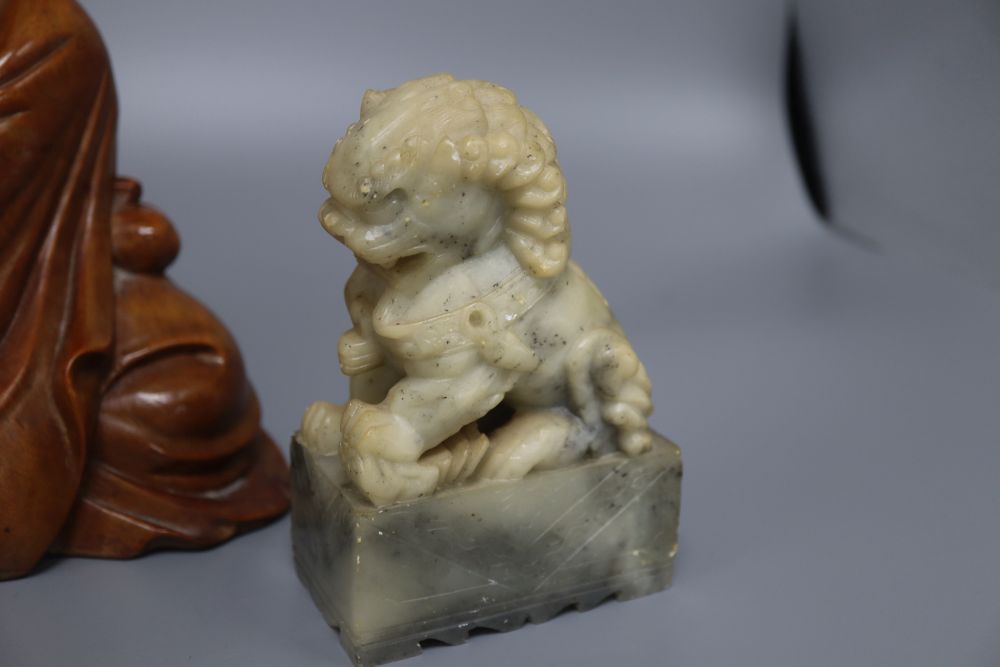 A Japanese rootwood carving of a seated elder, inset eyes and teeth and a pair of Chinese soapstone shishi, each crouched on a rectangu